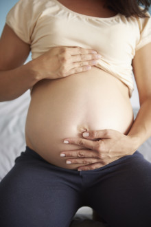 woman stroking her naked pregnant abdomen